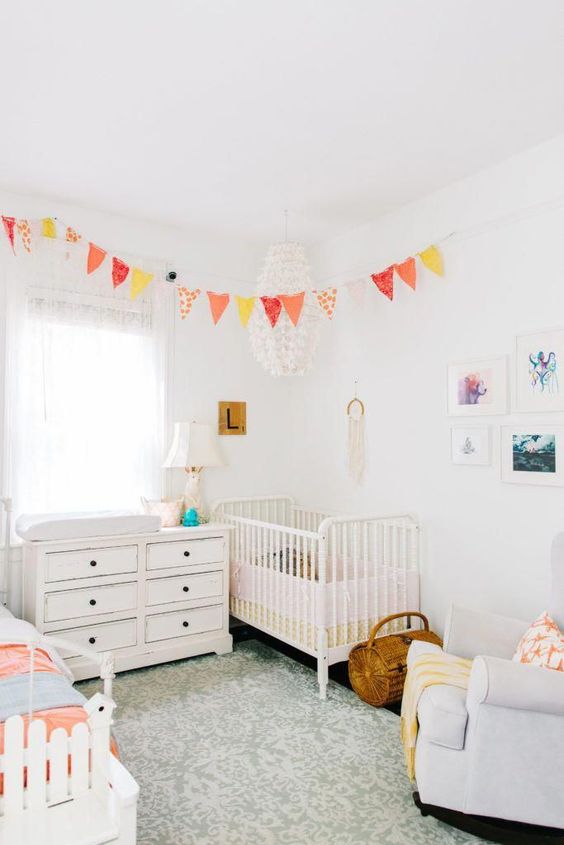 a neutral shared room with a couple of bright touches - a colorful bunting and bedding for a chic look