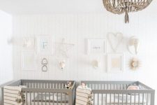 a peaceful twin nursery with grey cribs, a beaded chandelier, gallery walls and neutral bedding is relaxing