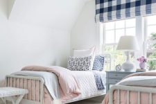 a preppy shared girls’ bedroom with white vintage furniture, a checked curtain and pastel and gingham printed bedding