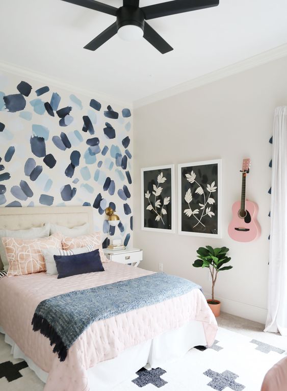 a pretty teen bedroom with a brushstroke accent wall, pink and blue textiles and a pink guitar on the wall
