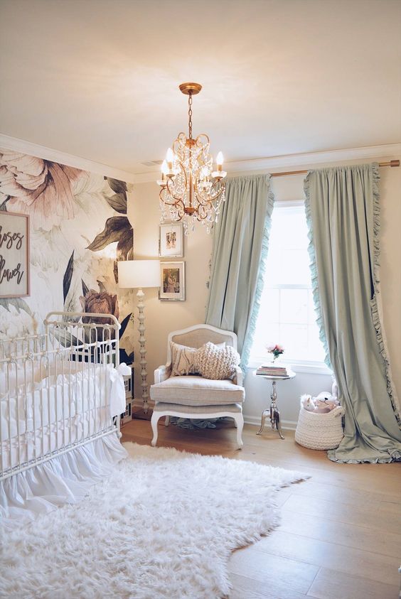 a refined nursery with a floral wall, vintage neutral furniture, a crystal chandelier, mint green curtains and a faux fur rug