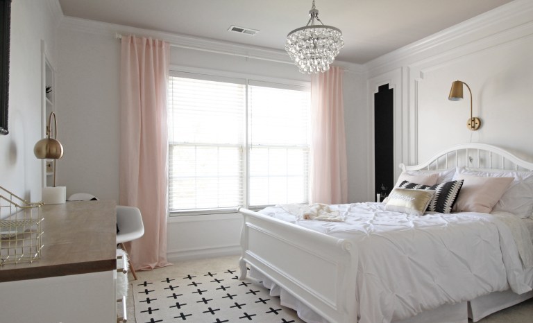 a refined teen girl bedroom in black, white and blush, with a large comfy bed, a crystal chandelier and touches of brass