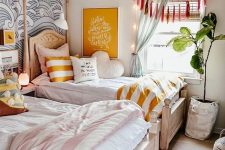 a relaxed and welcoming shared girls’ bedroom with stained wooden beds, printed and neutral bedding, an accent wave wall, tassels and curtains, a mint pendant lamp