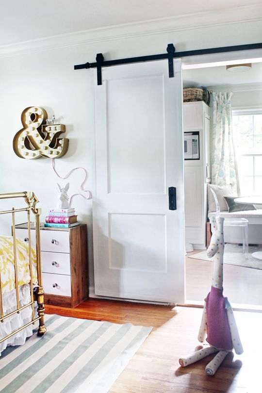 a simple white sliding door saves space in a small nursery and matches the interior very well
