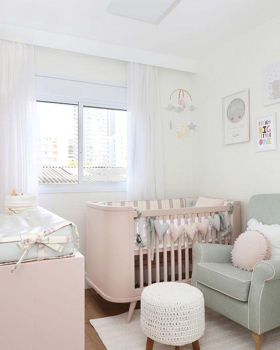 a small and pretty baby nursery with pastel furniture, a pastel heart garland, neutral textiles and a bright gallery wall