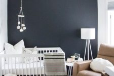 a small yet welcoming nursery with a navy accent wall, a brown leather chair and some white furniture