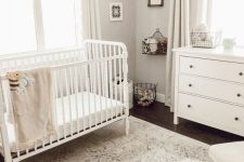 a stylish gender neutral nursery with grey walls, white vintage furniture, some art and toys that match