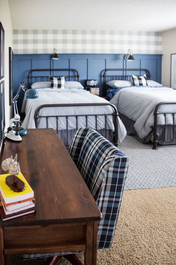 a stylish shared teen boy bedroom with black beds, a sained desk, a plaid accent wall and bedding