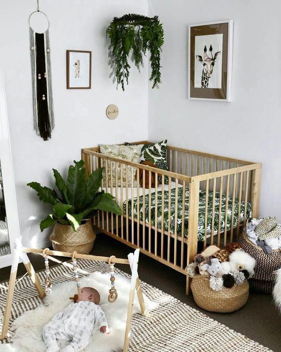 a tropical boho nursery with tropical bedding, baskets for storage, printed rugs, potted greenery is a stylish space