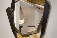 a uniquely shaped geometric mirror of an asymmetrical shape and a gold and black geo frame is amazing as an artwork