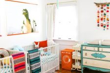 a vibrant twin nursery with colorful linens and bright furniture, a colorful mobile and an artwork