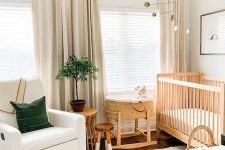 a welcoming gender neutral nursery with wooden and white furniture, a printed rug, baskets and a green pillow