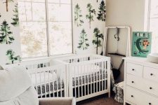 a woodland shared nursery with a tree statement wall, white furniture, artworks and much natural light