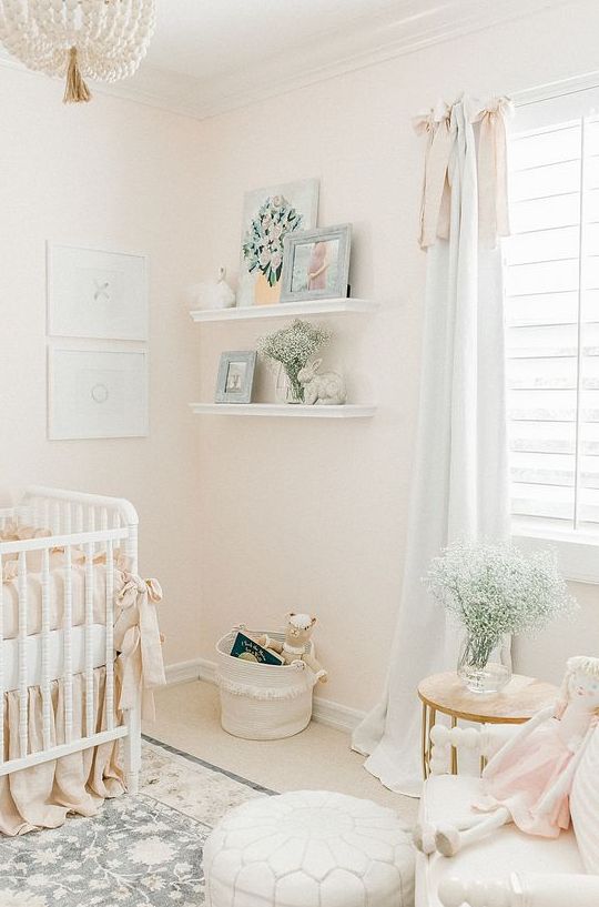 an airy neutral nursery with white furniture, open shelves, a mini gallery wall and a beaded chandelier is chic