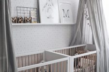 an all-neutral nursery with printed walls, white and stained furniture, grey canopies, a ledge with artworks and printed bedding