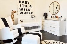 an elegant and refined monochromatic nursery with an acrylic crib, black and white art, a rug and a bold rocker