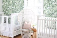 an ethereal boho nursery with a banana leaf wall, white furniture, a gold side table and white linens