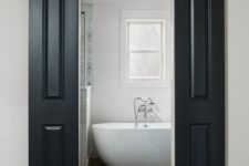black sliding barn doors contrast the neutral space and hide the entrance to the bathroom