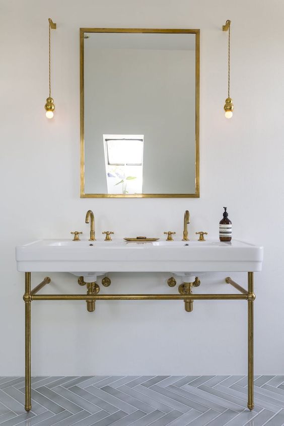 Wall mounted pendant lamps in gold match the vanity and the mirror frame and look chic