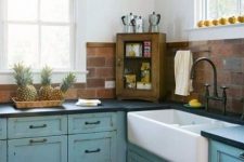 a blue shabby chic blue kitchen with dark countertops and a red faux brick backsplash for a texture