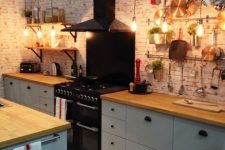 a pretty IKEA Metod kitchen in light grey, with black handles, butcherblock countertops, a whitewashed kitchen backsplash and black appliances