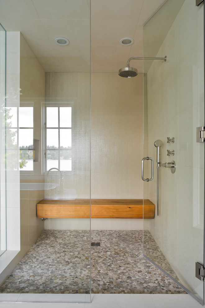 Pebble tiles on a floor mixed with white ones on walls to create this cool walk-in shower. Although a wooden bench is what makes it so cozy. (Laura Bohn Design Associates)