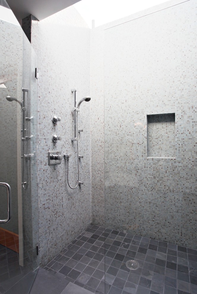 A modern walk-in shower with walls covered in mosaic tiles in different colors. (Wallace Remodeling, Inc.)