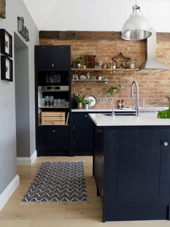 midnight blue kitchen with shaker style cabinets, white countertops, a red brick backsplash and potted plants, stainless steel appliances