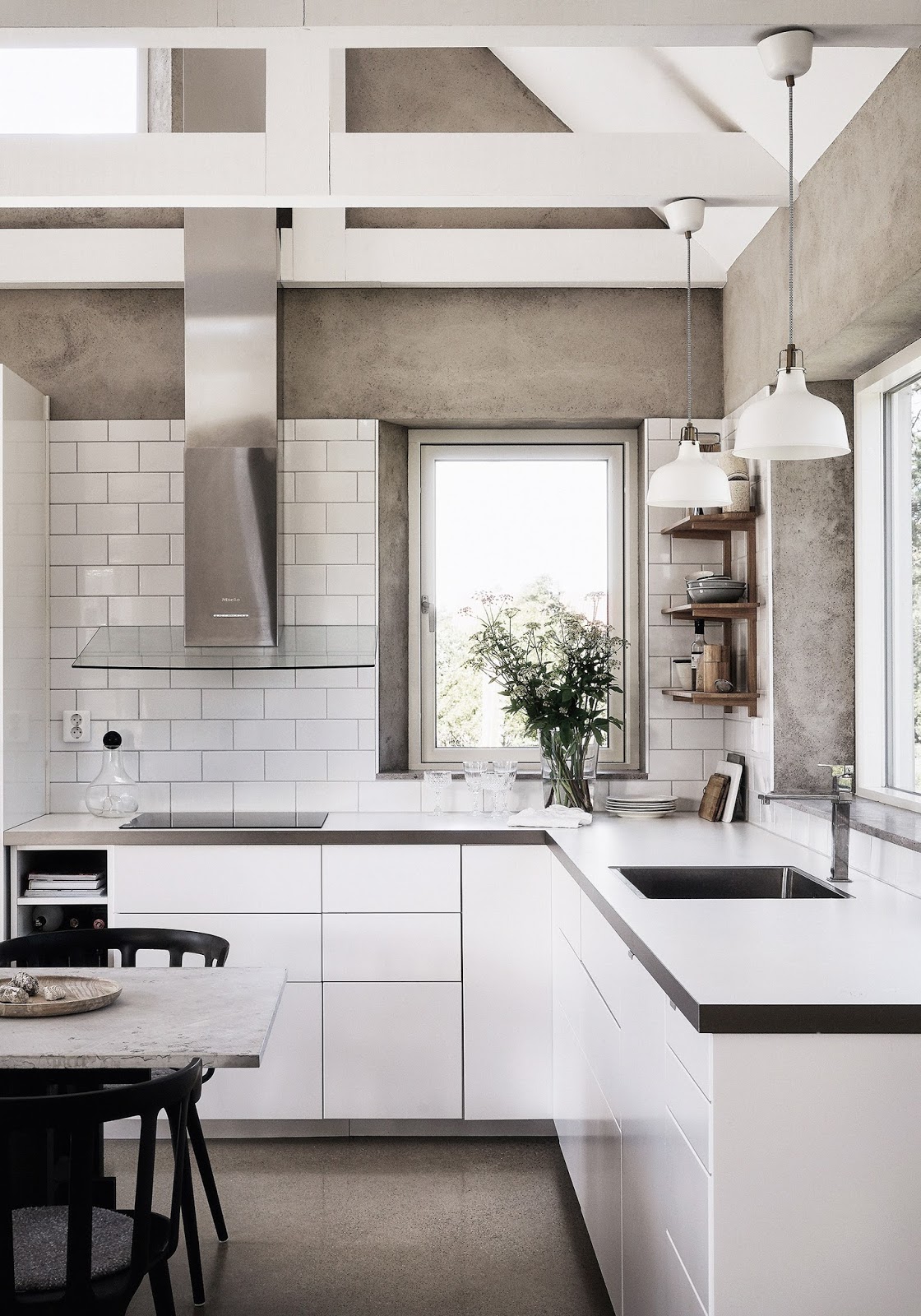 03 The kitchen is white and modern, concrete walls mix with white tiles and cabinets