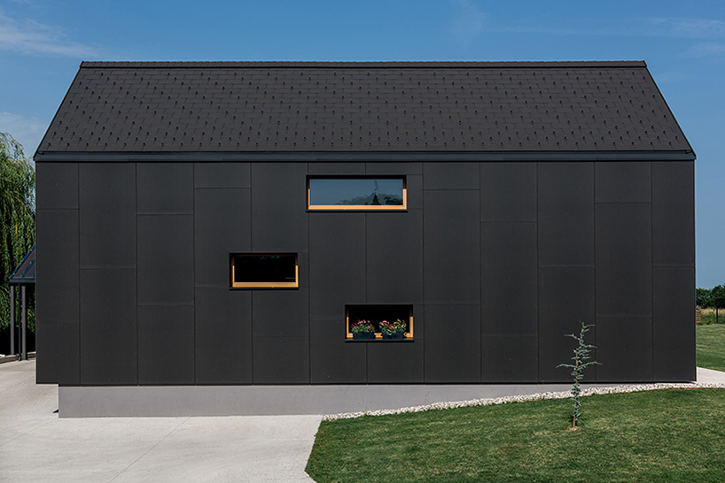 The structures with dark exterior are elongated with symmetrical gable roofs