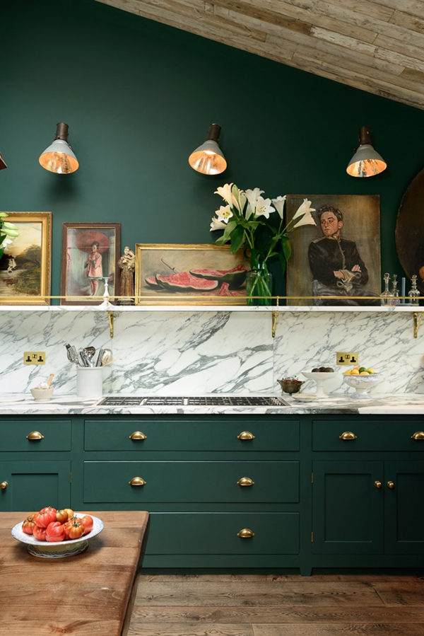 Antique artworks create an ambience, and a marble backsplash contrasts with the dark green cabinets