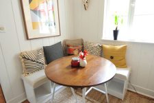a modern rustic breakfast nookwith a sisal rug and a wood top table plus a corner seating with lots of pillows and a bright artwork