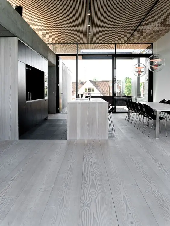 modern kitchen with grey wood floors going up to the walls and the kitchen island