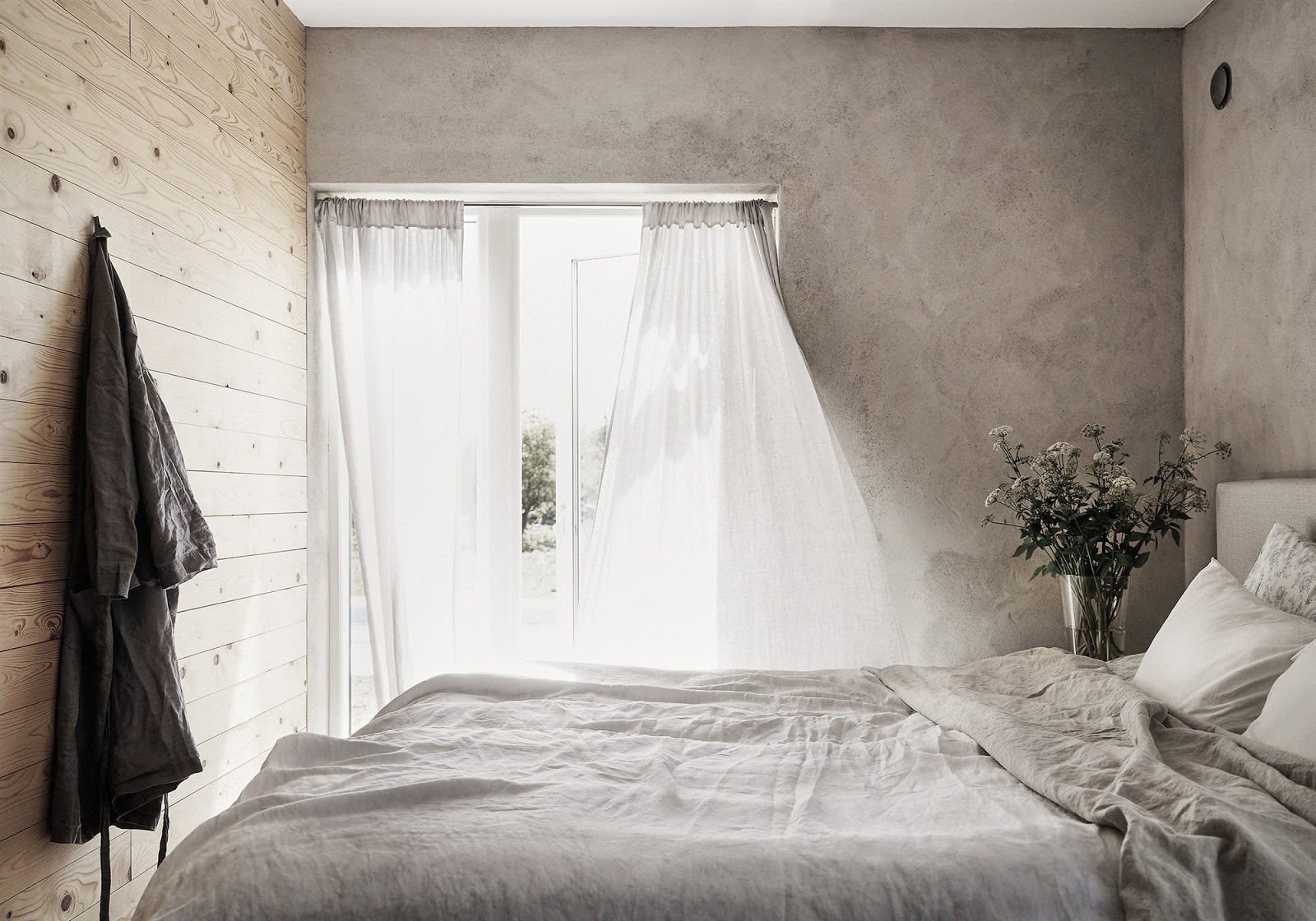 The master bedroom is decorated with concrete, fabrics give texture to the decor