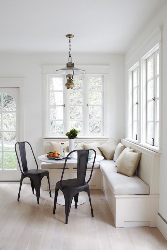 a modern neutral breakfast corner with black chairs, a round table, lots of pillows and a vintage pendant lamp is welcoming
