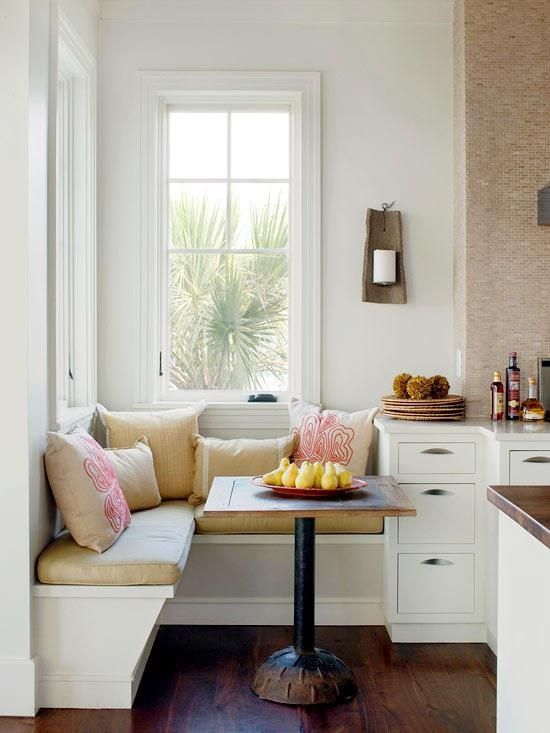 a super small breakfast nook with patterned pillows on a banquette corner seating and a small table can be squeezed into a kitchen