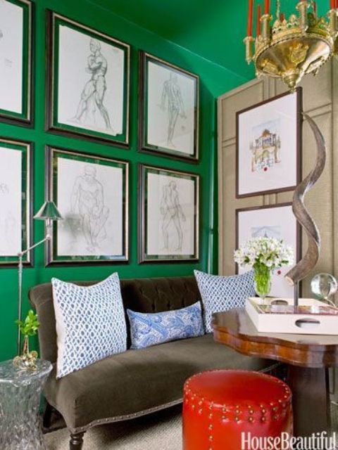 An emerald accent wall is balanced with a leather ottoman in a neutral colored room