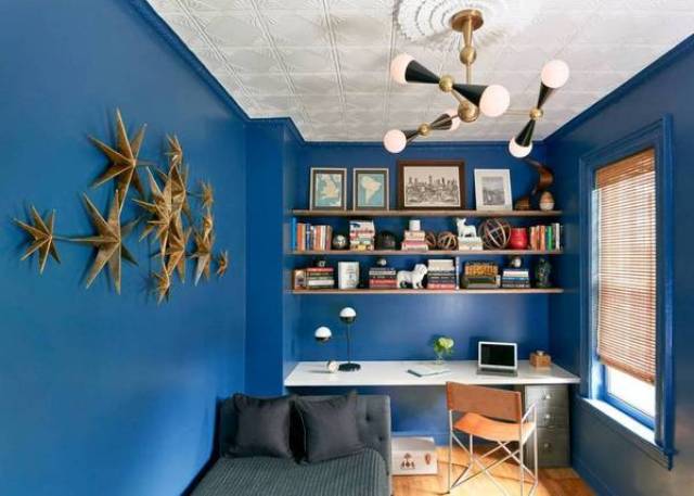 The home office is dazzlign blue with a cool lamp and a 3D wall art