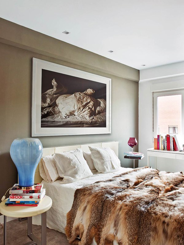 The bedroom is cozy with an olive accent wall and a gorgeous fur bedspread