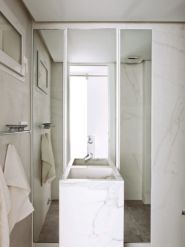 The bathroom is small and elegant, clad with white marble