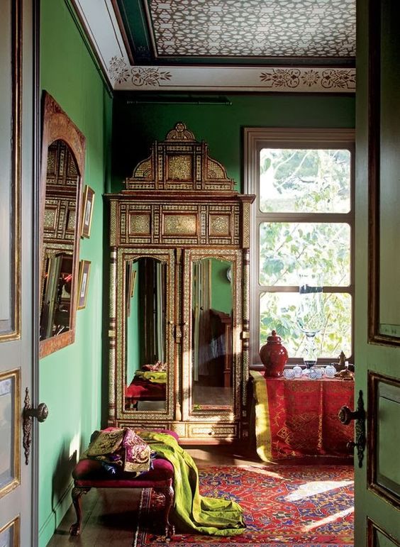 Moroccan-styled interior with sage green walls and red upholstered furniture and textiles