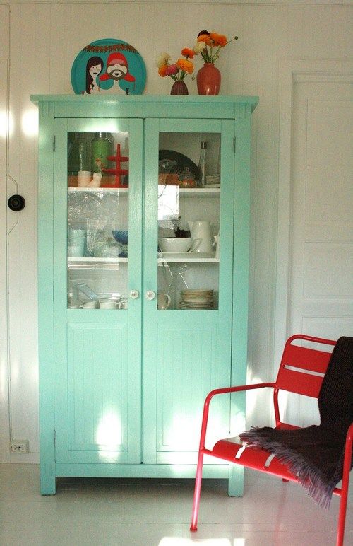 Neutral interior with a mint cupboard and a statement red chair