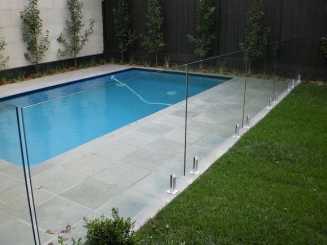 stone pavers deck and a glass fence for a pool