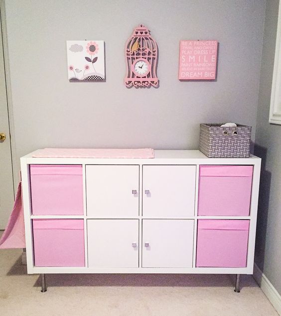 an IKEA Kallax diaper changing table in pink and white, with boxes and doors, will be a neat and sleek storage unit and will be a great changing table