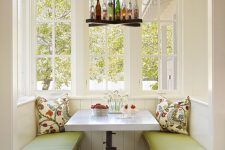 a rustic breakfast nook with built-in benches and a white table, a creative bottle pendant lamp and colorful printed pillows