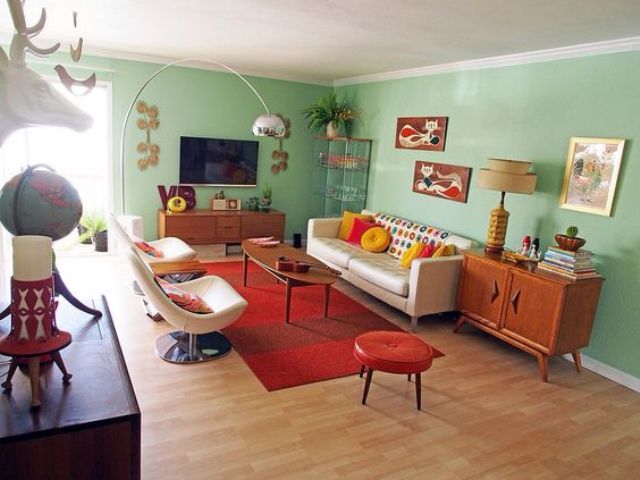 Mint green walls of this mid-century modern living room are balanced with a red rug and ottoman
