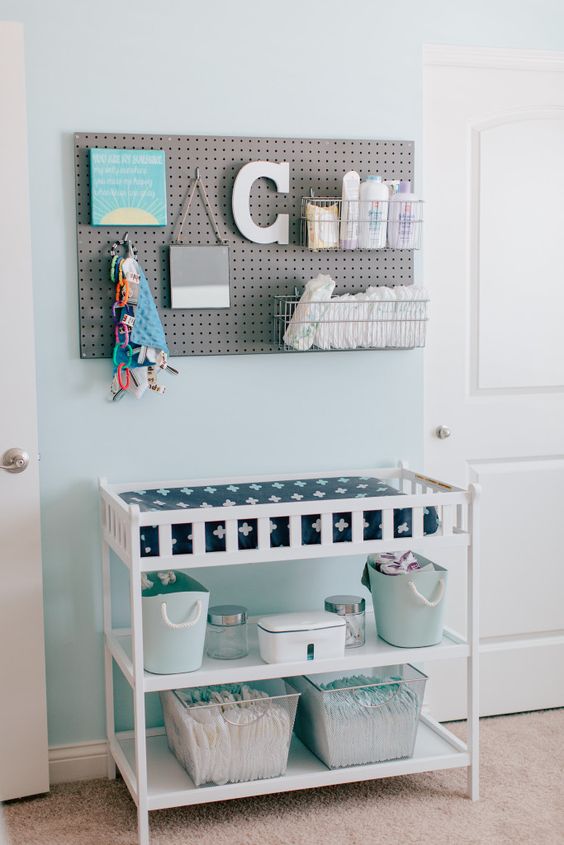 modern white changing table with a pegboard over it for storage