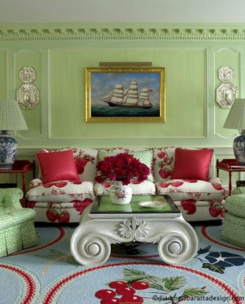 Soft green room decor accentuated with red rugs and pillows