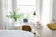 a Scandinavian grey bedroom with a bed and a printed rug, a white desk and vanity at the window, a stained chair and some greenery