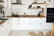 a Scandinavian kitchen with white cabinets, butcherblock countertops, a subway tile backsplash and a cool floor transition from hex tiles to laminate